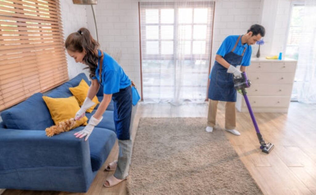 Male and female cleaning staff are wiping surfaces in a home.