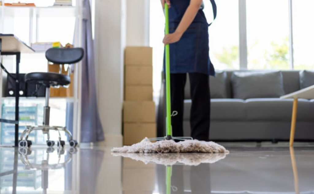 A person is mopping the living room floor with a mop.