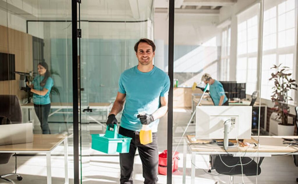 A janitor is cleaning an office with a mop and a bucket.