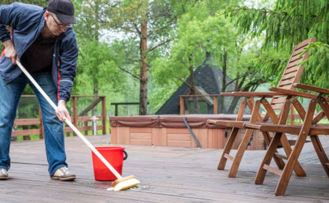 A man cleaning a wooden terrace with a high-pressure washer
