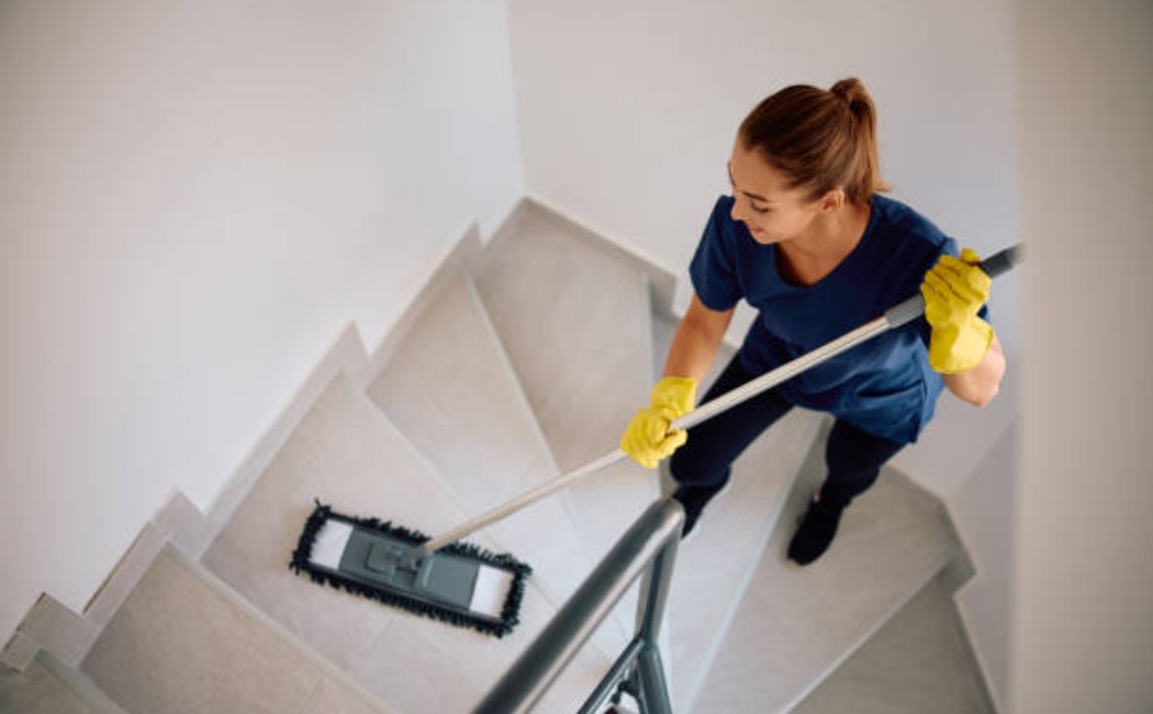 Cleaning staff wiping stair steps with a mop.