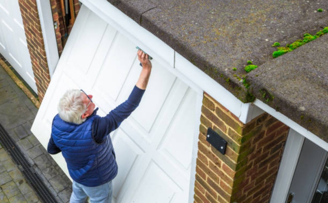 A senior man is cleaning a dirty garage door at home