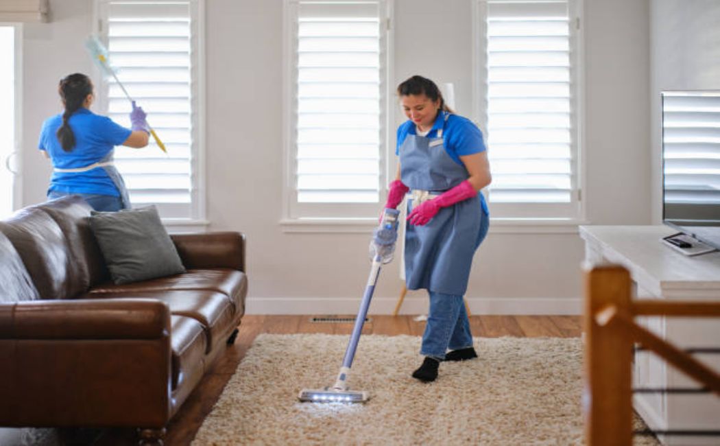 Professional cleaners tidying a modern living room in a home.