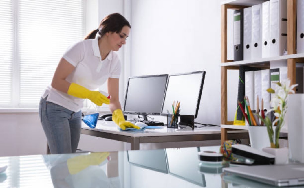 Woman cleaning a computer keyboard in an office.
