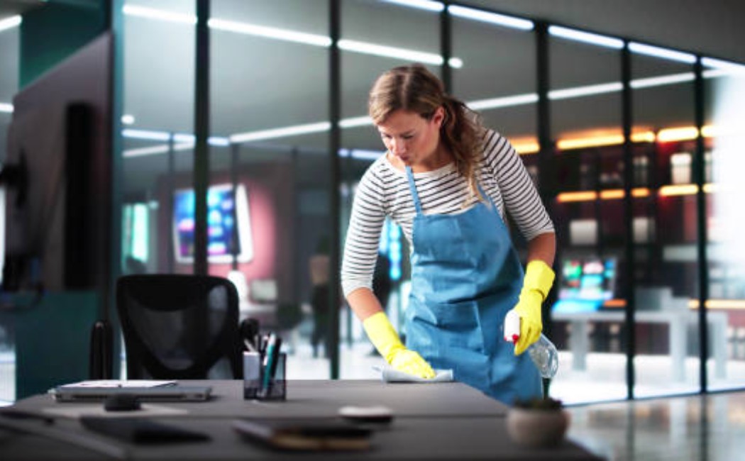 Office cleaner wiping down a workstation during routine cleaning.