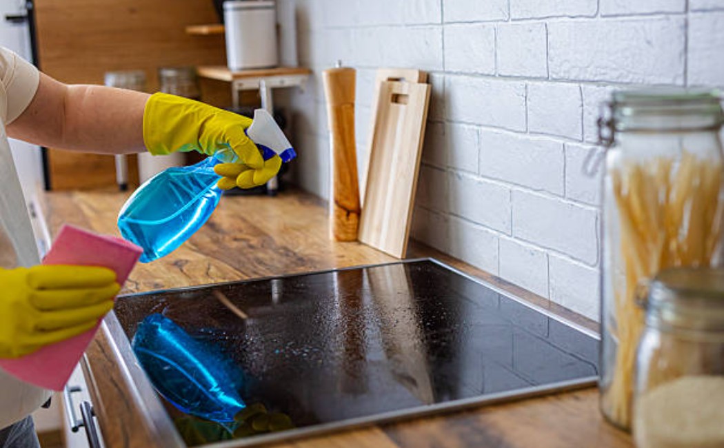 Kitchen maintenance: cleaning stovetop with yellow gloves