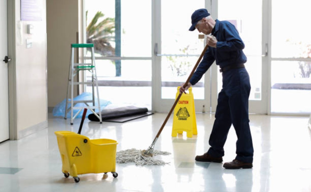 Senior maintenance worker cleaning hallway