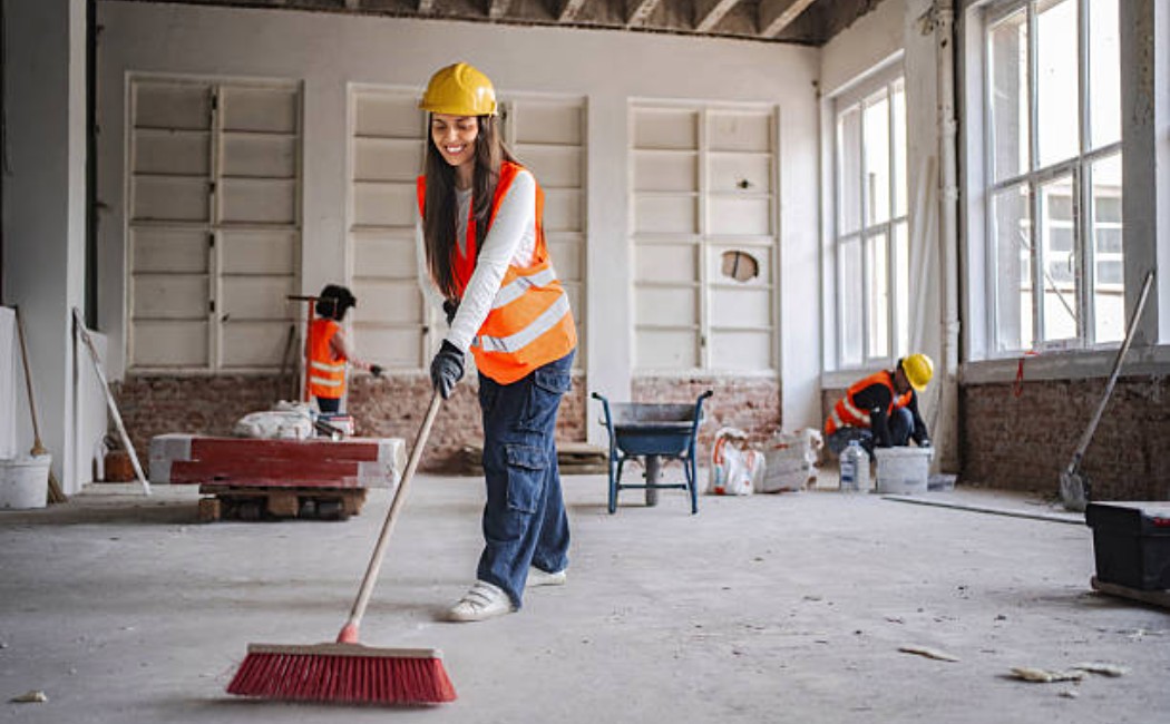 A woman laborer cleaning debris on a construction site floor
