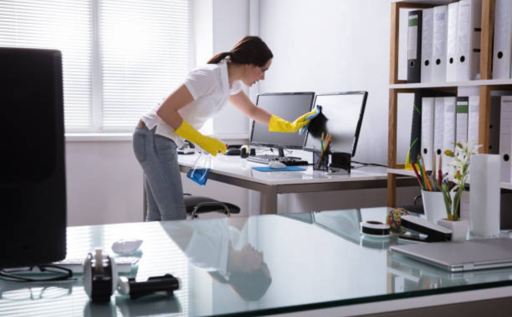 Woman wiping a computer screen in a modern office